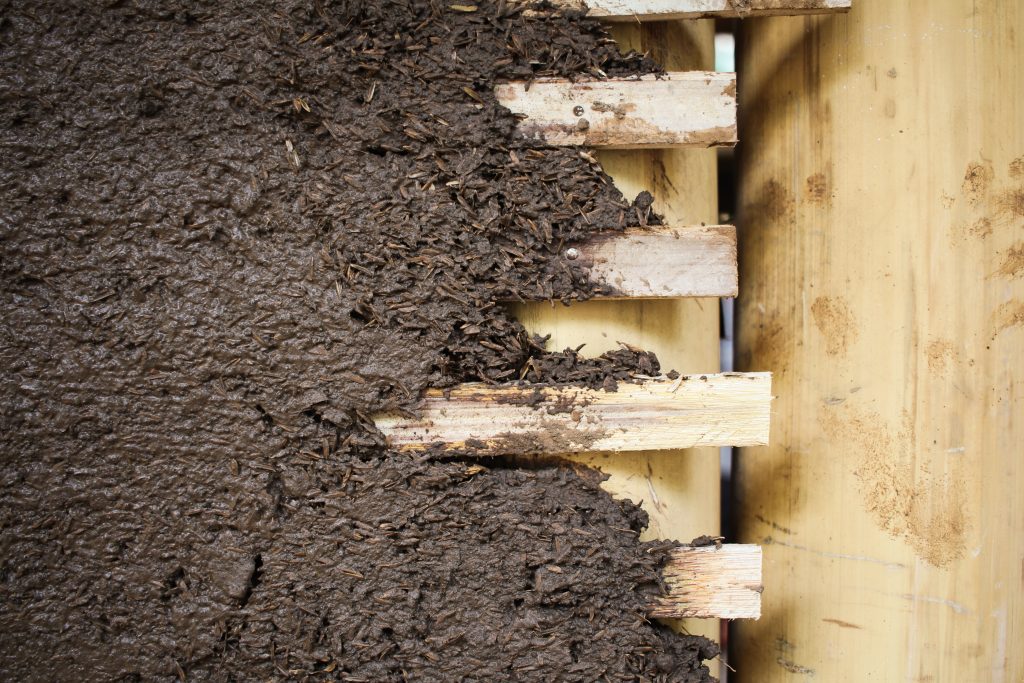 mud mixture to a woven bamboo wall frame